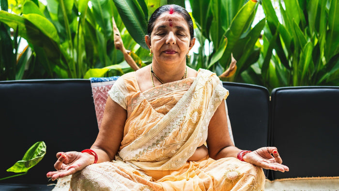 Woman in a sari meditating in a garden, the quiet devotional practice linked to the Mahavidya goddesses