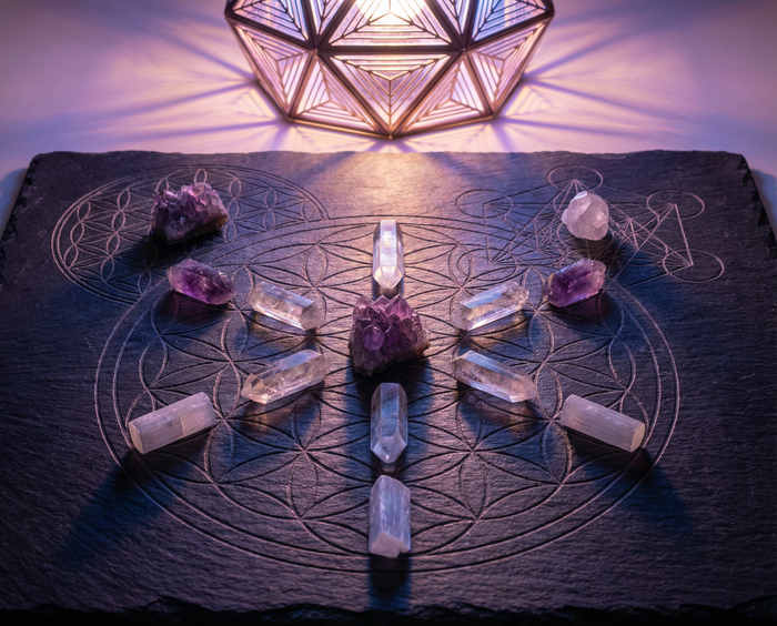 Crystal grid of quartz points and amethyst on a slate board engraved with the Flower of Life