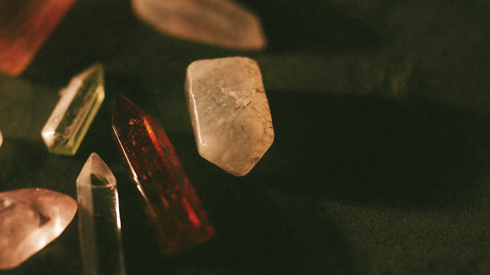 Different polished crystals lying loosely together on dark linen, one pale stone marked with fine scratches