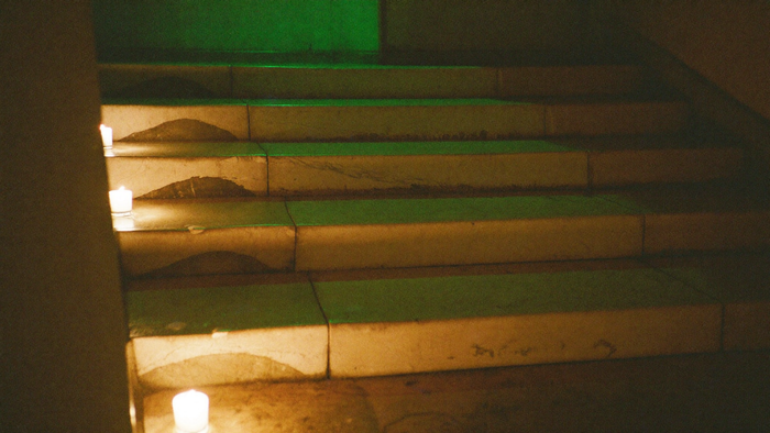 Worn pale stone steps rising into shadow, lit by small candles set along their left edge