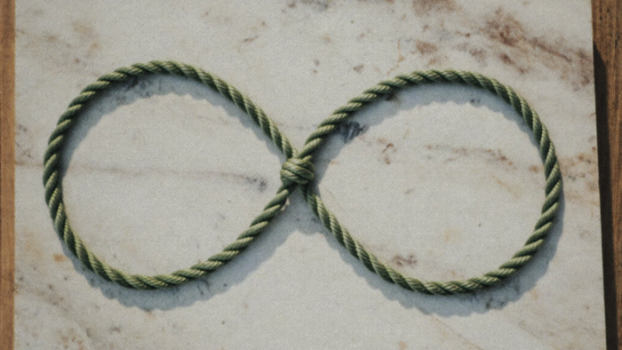 A green braided rope tied into a figure eight loop on a pale marble slab, seen from above