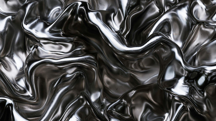 Close-up of a rippling, mirror-bright liquid silver surface with deep folds catching soft light