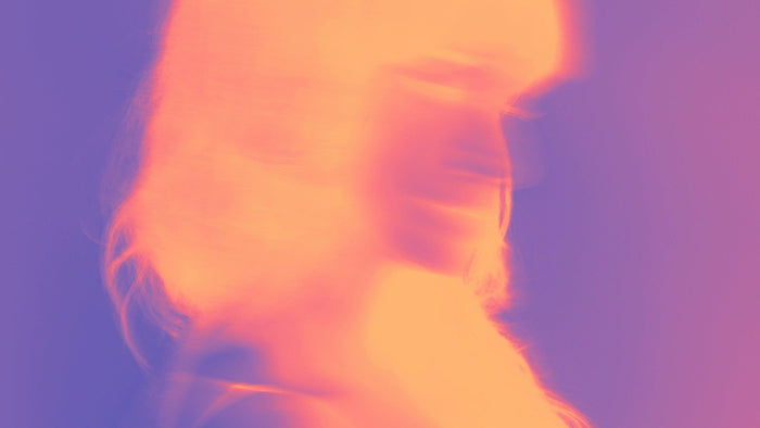 Soft-focus profile of a figure dissolving into warm orange and violet light, an image of awareness beyond form