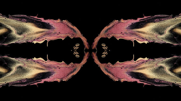 Mirrored ink pattern in rose and gold on black, two identical halves facing each other