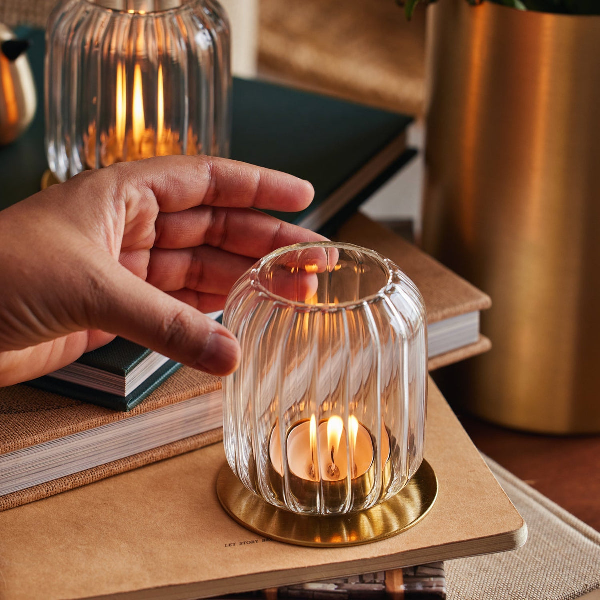 Hand setting a Kira glass lantern down beside a lit one