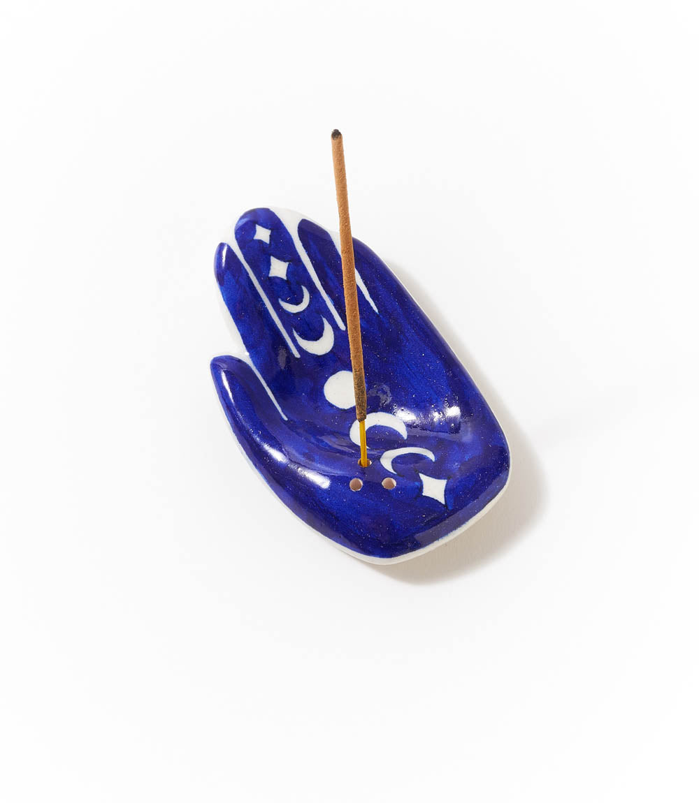 Hamsa hand ceramic incense holder with an incense stick standing upright