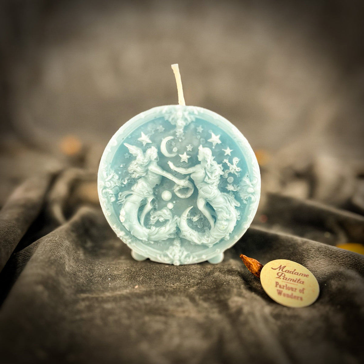 Pale blue Gemini medallion candle, the figures and stars lighter than the field.