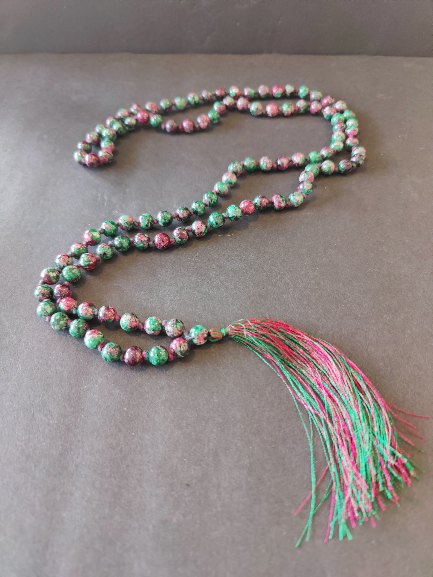 Long mala necklace strung with assorted natural stone beads, hanging in a loop — view 5