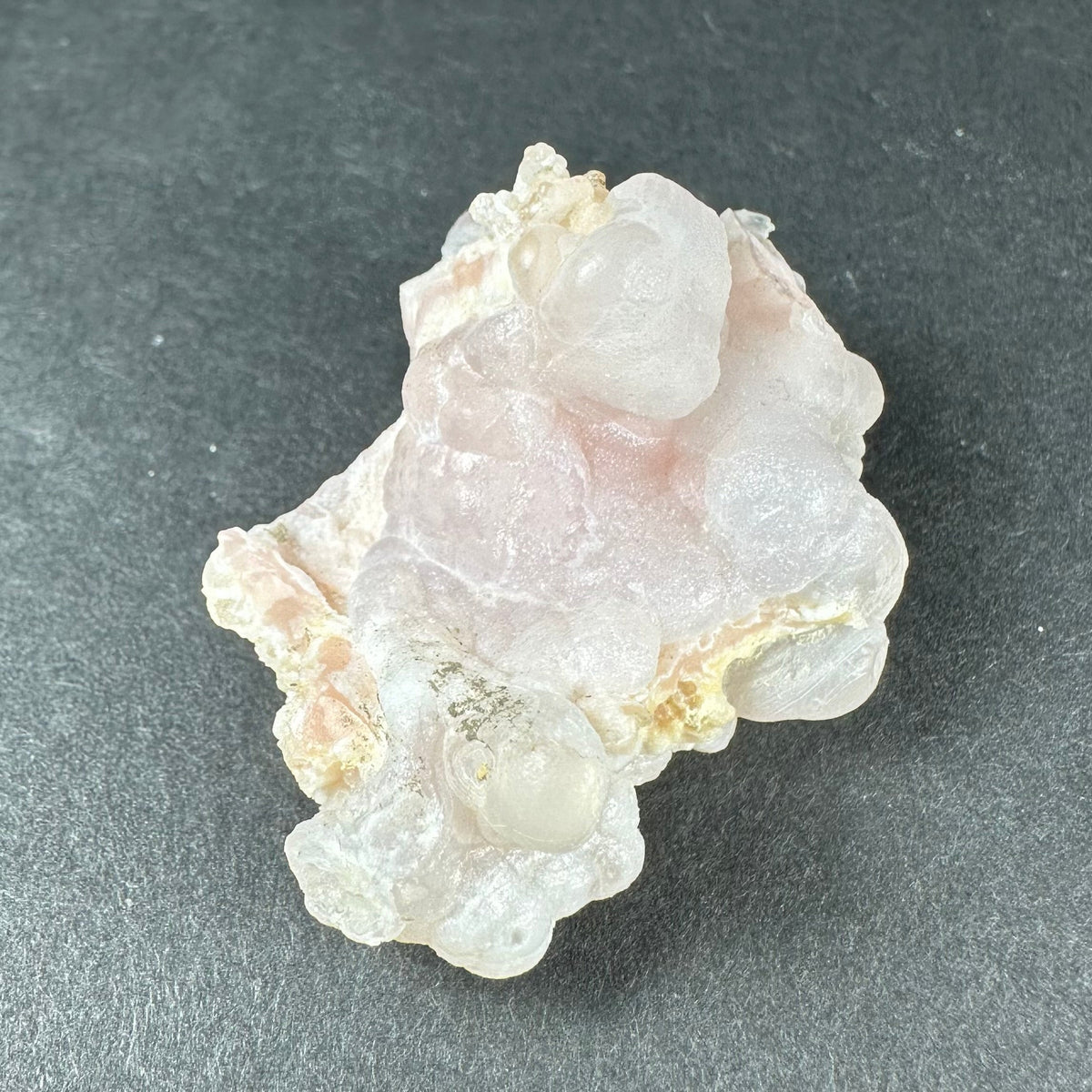 Pink opal specimen with a translucent pale core, the bubbled crust wrapping around it