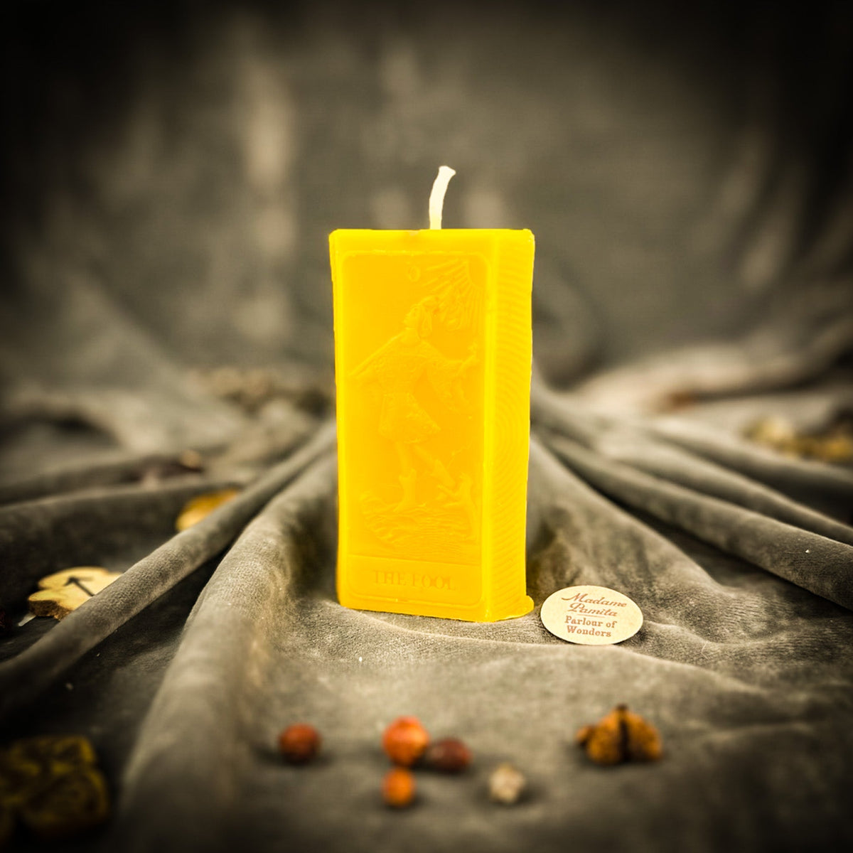 The Fool beeswax tarot candle in yellow on draped gray fabric