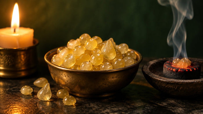 Pale yellow mastic resin tears in a brass bowl beside a glowing charcoal with rising smoke and a lit candle