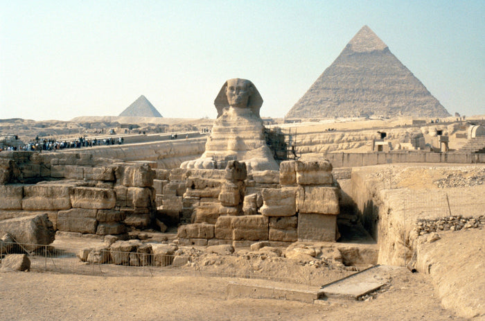 The Great Sphinx and the pyramids of Giza seen across the excavated limestone plateau at midday