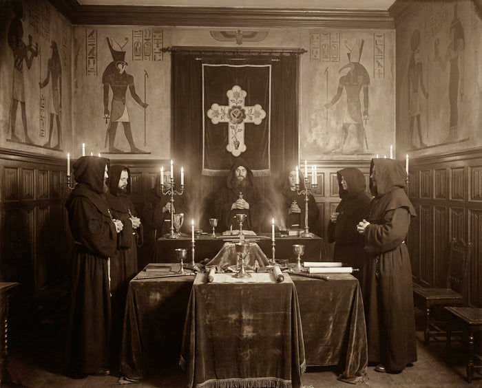 Robed figures with candles around a draped altar, a rose cross banner and painted Egyptian figures behind