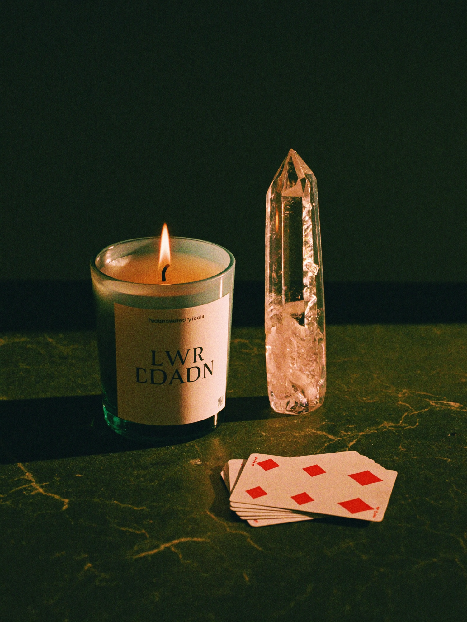 Tarot cards laid out for a reading on polished dark marble, lit by a single warm golden light against a deep emerald-green background falling into shadow.