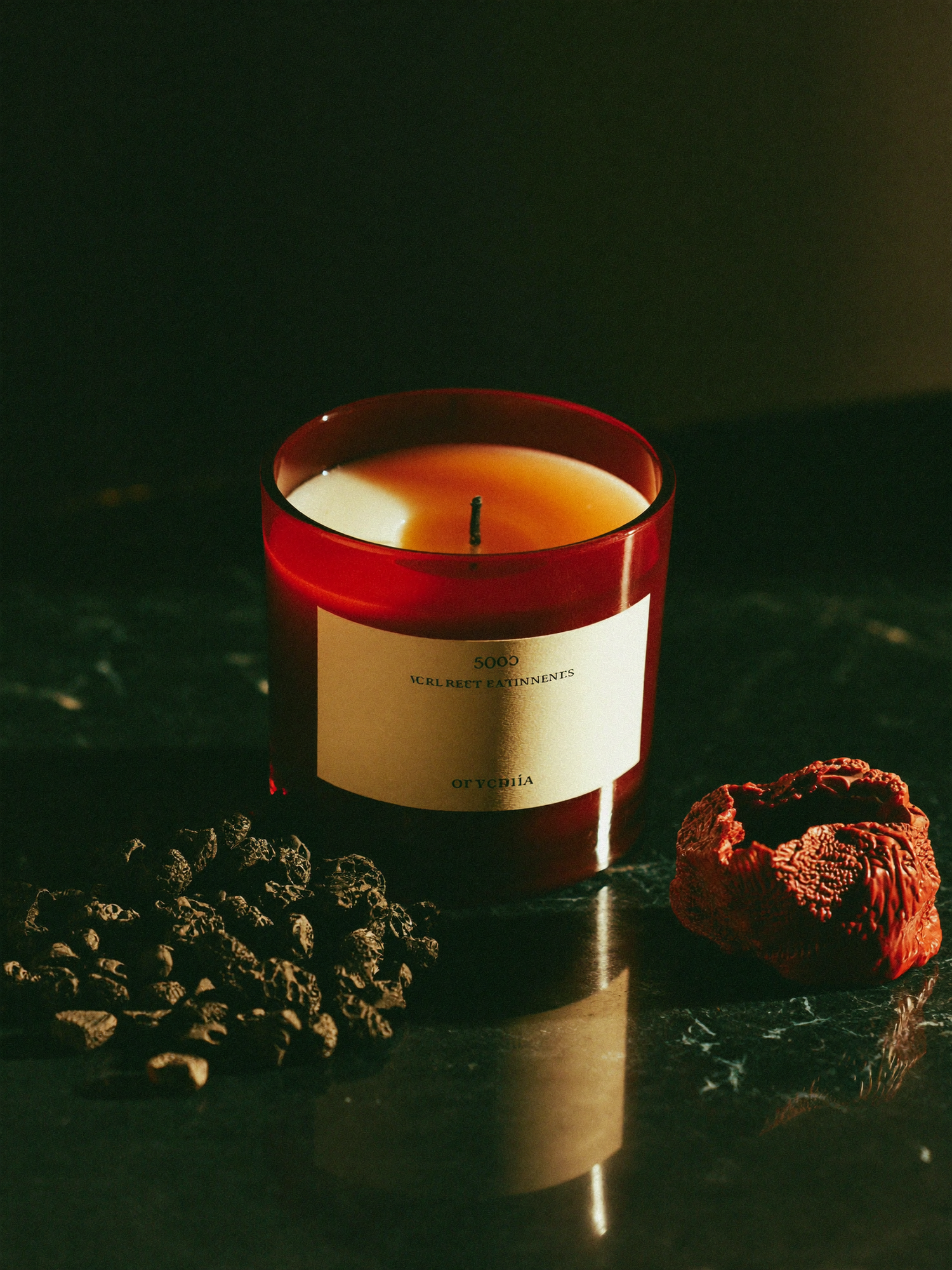A Fiery Wall of Protection candle burning on polished dark marble, its flame the brightest point against a shadowed emerald-green background.