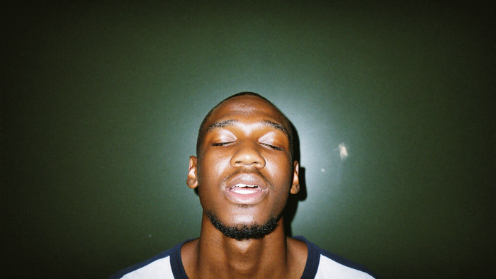 A young man with his eyes closed and head tilted back, quietly holding a sung tone