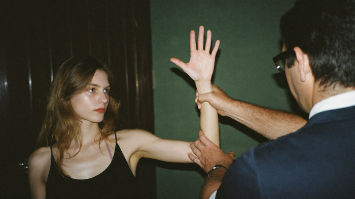 Practitioner pressing down on a young woman's outstretched arm at the wrist during a kinesiology muscle test
