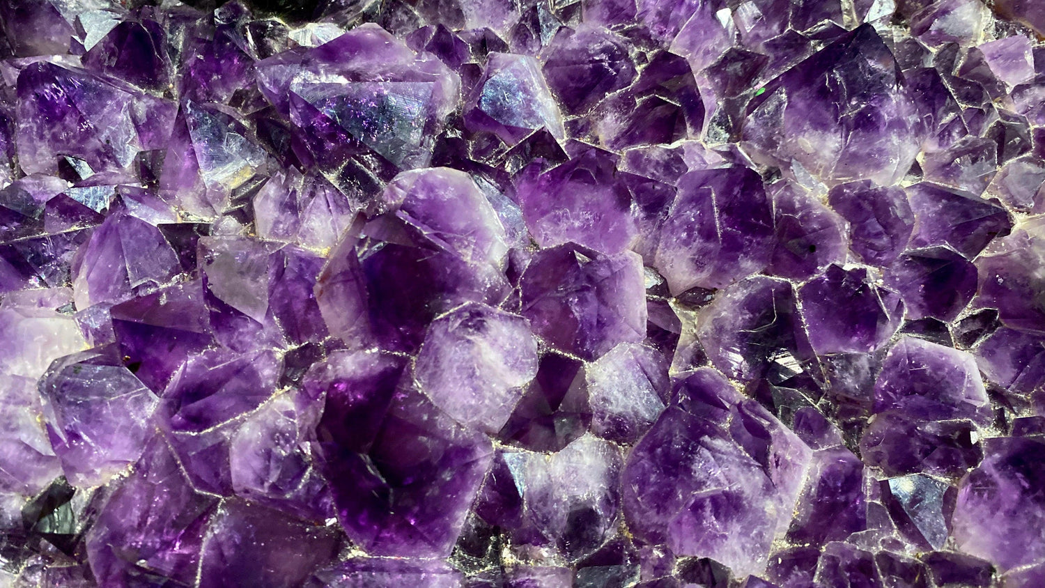 Close-up of a deep purple amethyst cluster with light catching the crystal points