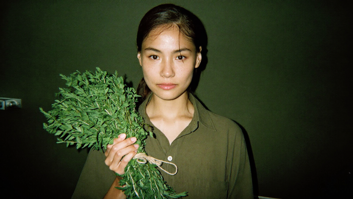 A woman holding a freshly cut bundle of mugwort tied with twine, ready for drying