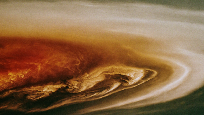 Close view of banded cream and rust cloud belts with one large oval storm turning among them