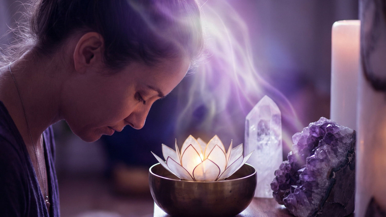 Woman meditating over a lotus candle with violet light rising, amethyst and clear quartz beside her