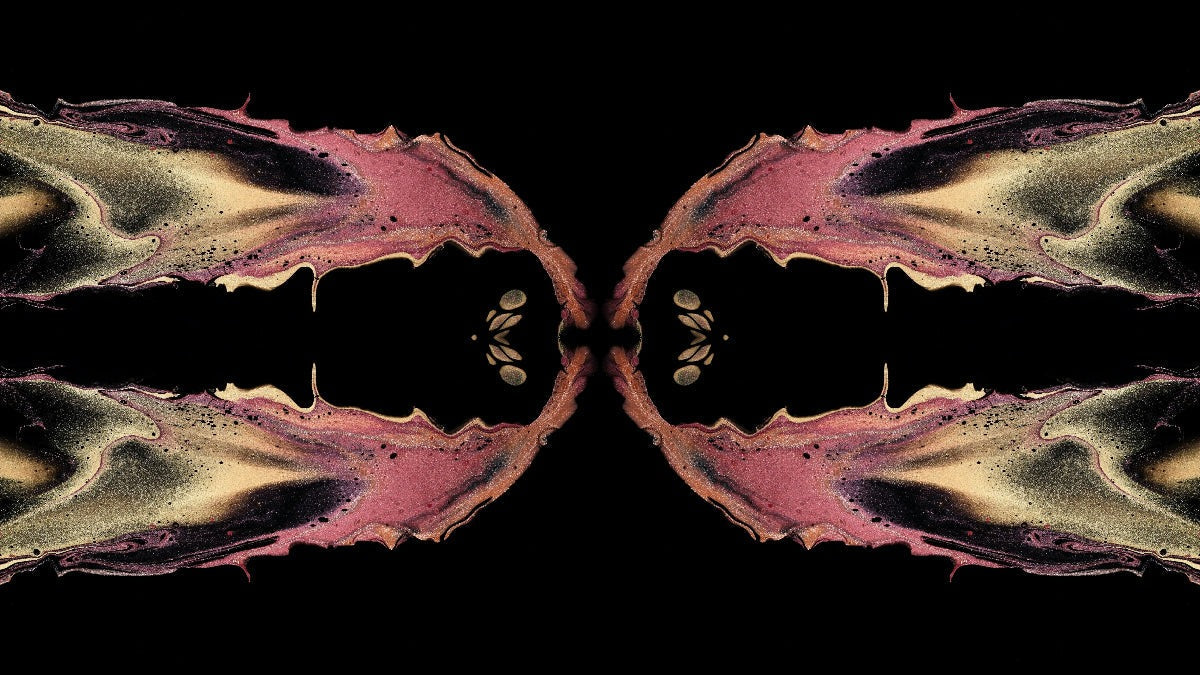 Mirrored ink pattern in rose and gold on black, two identical halves facing each other