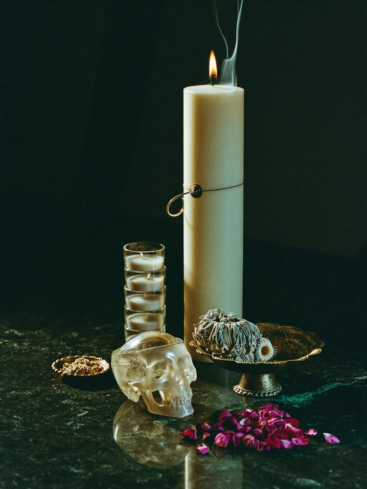 Curated altar arrangement with pillar candle, crystal skull and sage