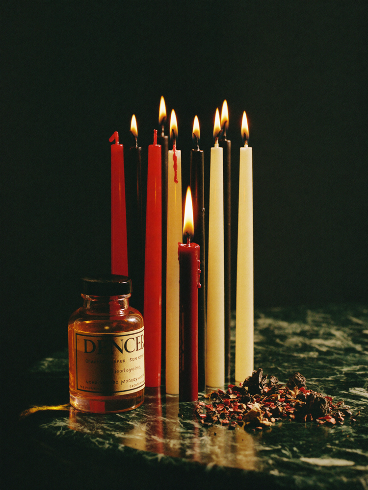 Seven-day ritual candles with anointing oil on dark marble
