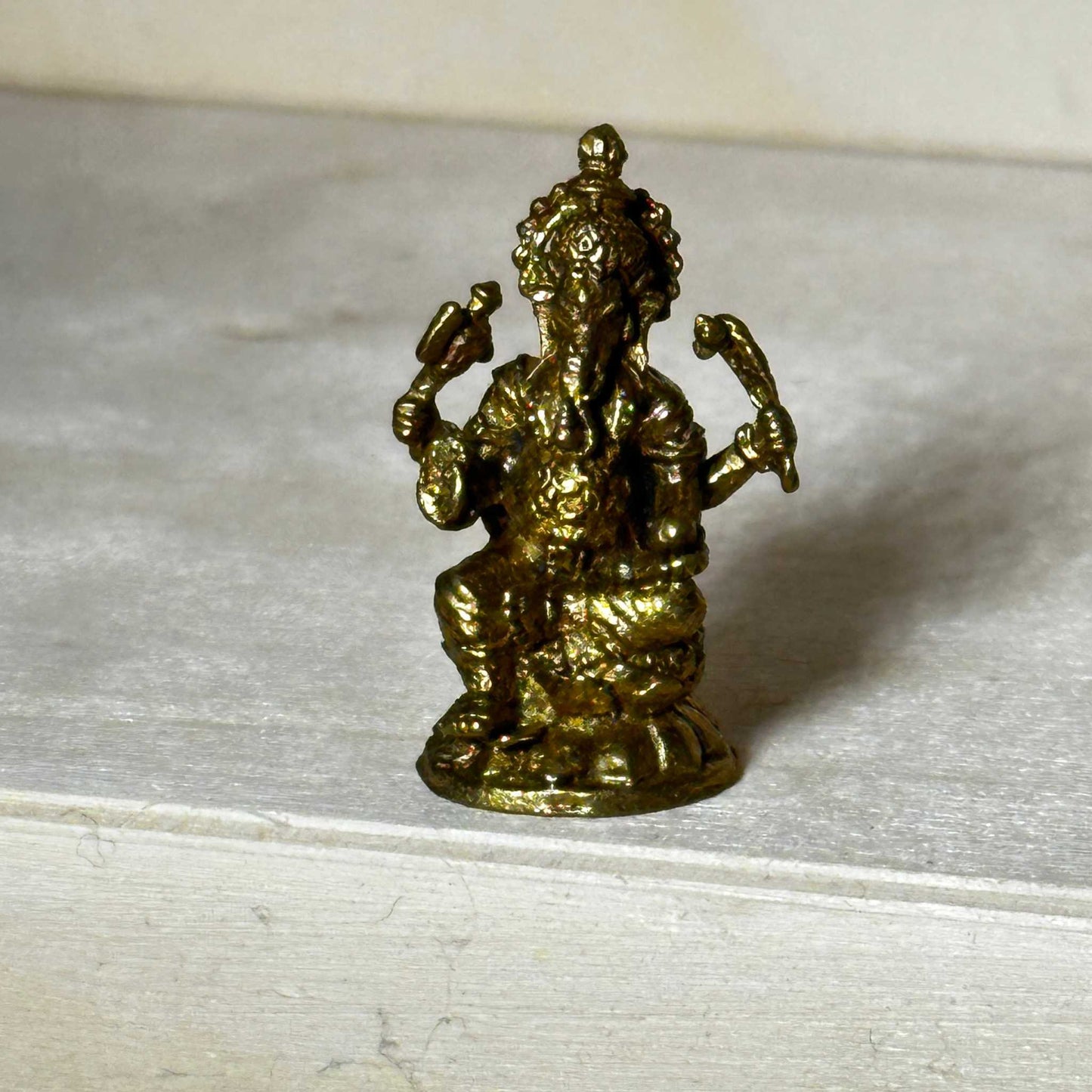 Small brass statue figurine sized to fit in the palm of a hand, further detail view