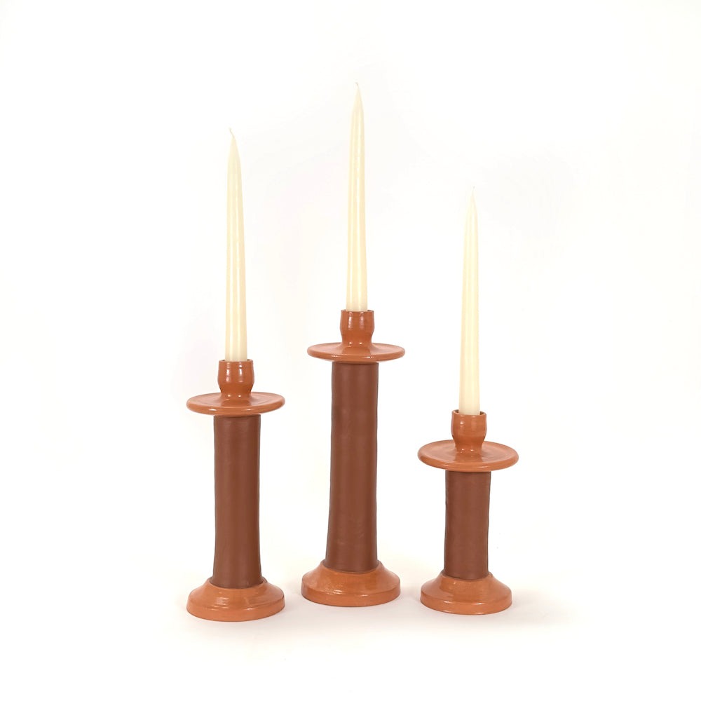 Three terracotta leather-wrapped holders in small, medium and large with cream tapers