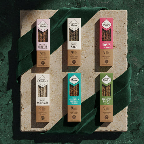 Six Herbs and Resins incense boxes laid on a pale stone slab over dark green velvet