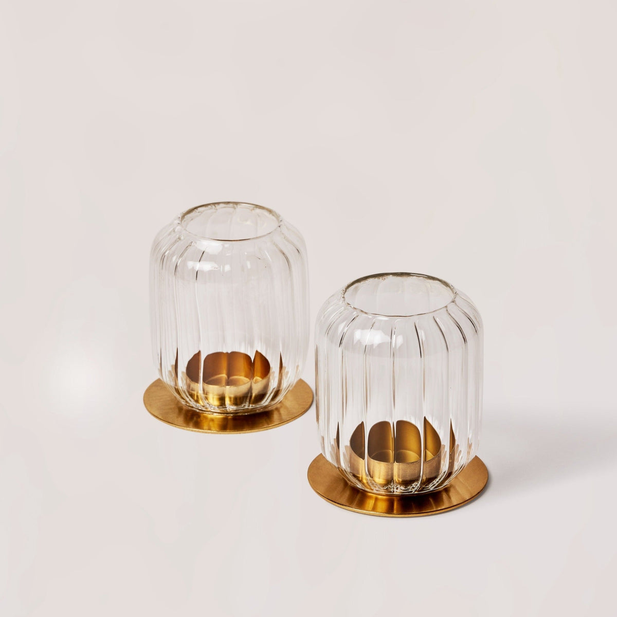 Two Kira glass lanterns on brass bases, one holding a tealight