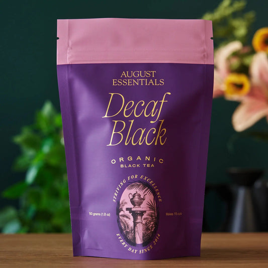 A purple August Essentials stand-up pouch of Decaf Black organic loose leaf tea.