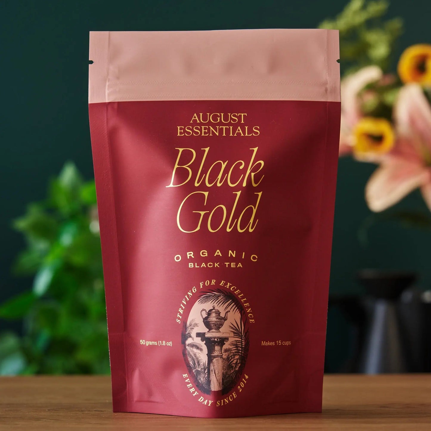 A crimson August Essentials stand-up pouch of Black Gold organic loose leaf black tea.