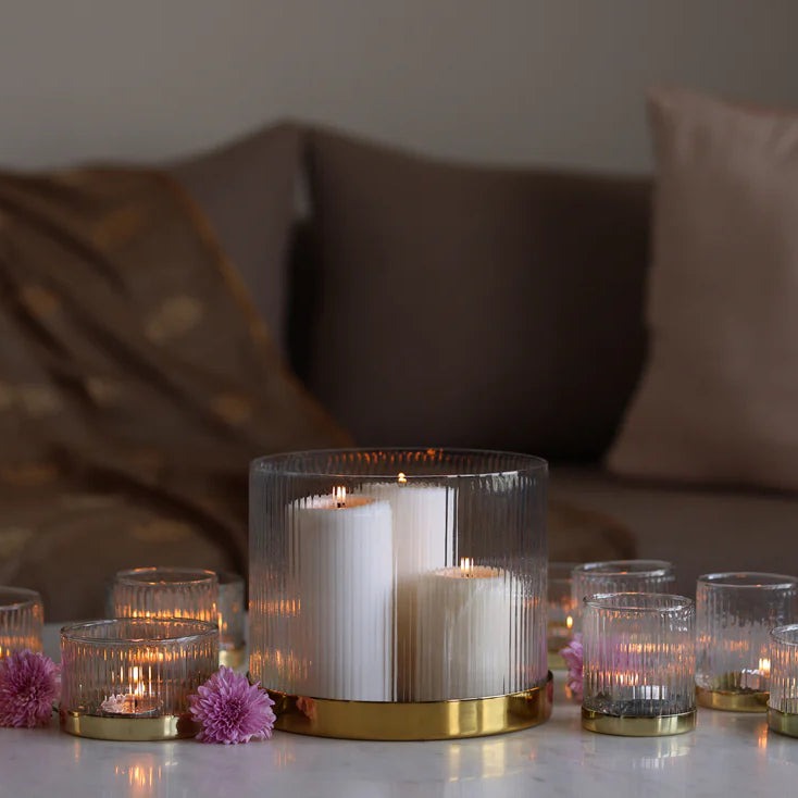 Fluted glass vase used as a hurricane with pillar candles among tealights