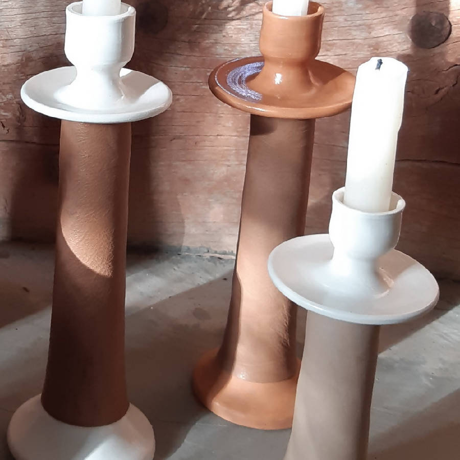 Close view of three leather-wrapped candle holders, showing the leather grain and ceramic bases