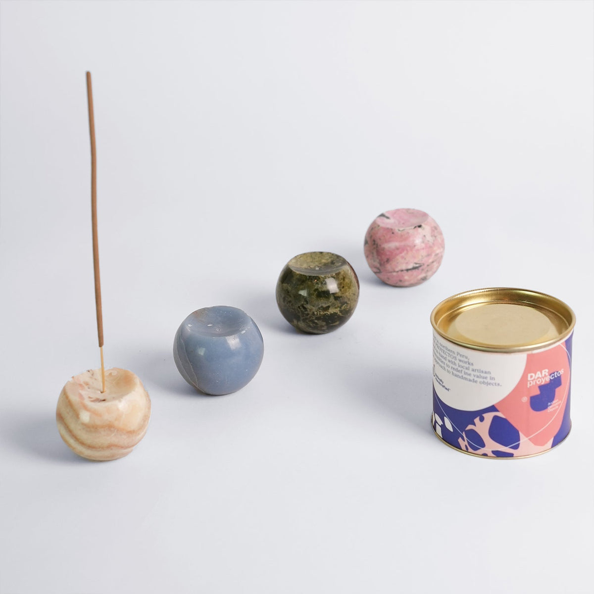 Cream onyx sphere holder shown with the pale blue, green and pink stone versions and its tin