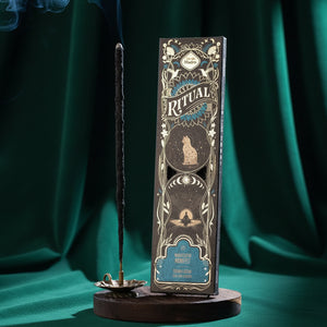 Manifest Ritual incense box smoking in a dark room with fresh herbs around it
