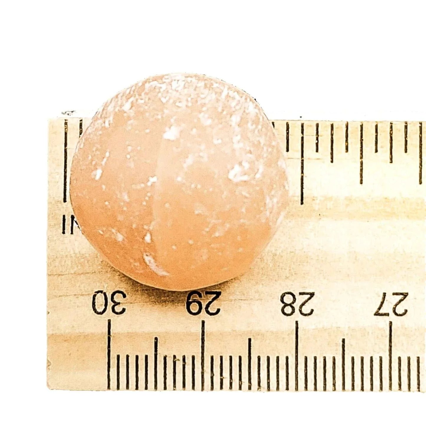 Peach selenite pocket sphere with a soft satin finish, detail view
