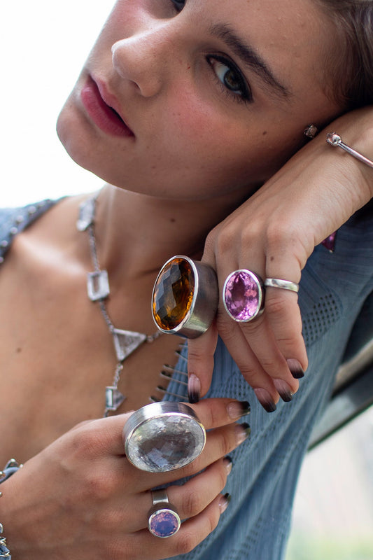 A statement ring with a carved azalea pink glass stone in a tall oxidized silver setting.