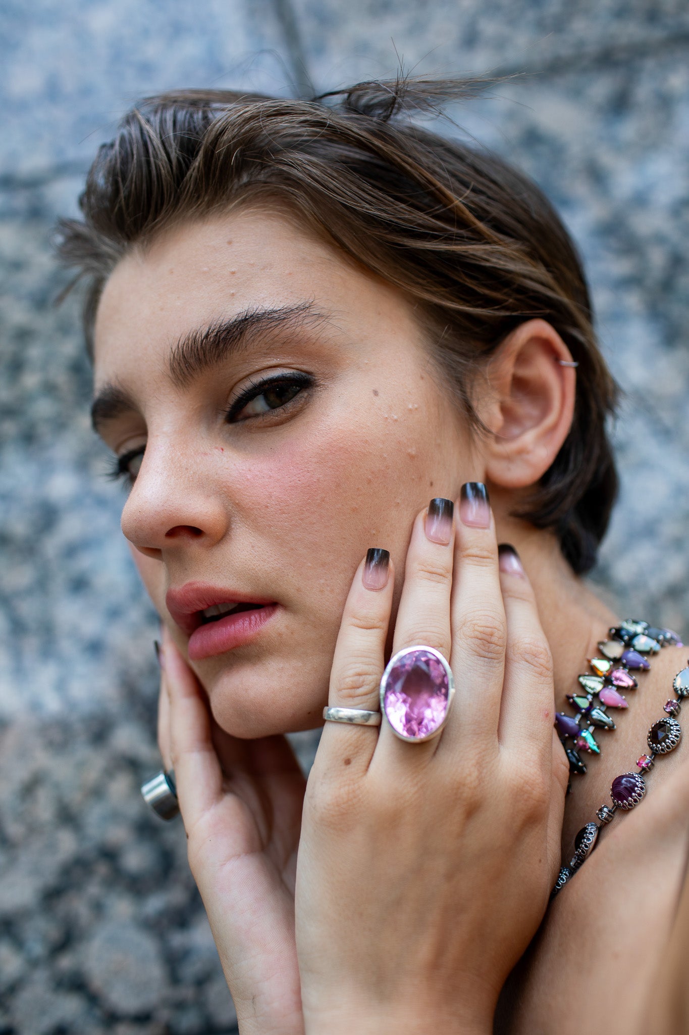A statement ring with a carved azalea pink glass stone in a tall oxidized silver setting, shown from a different angle.
