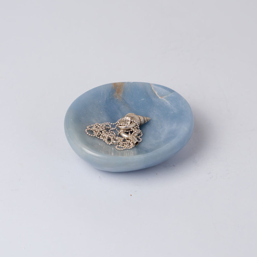 Angelite catchall holding a fine silver chain, showing the chalky matte surface