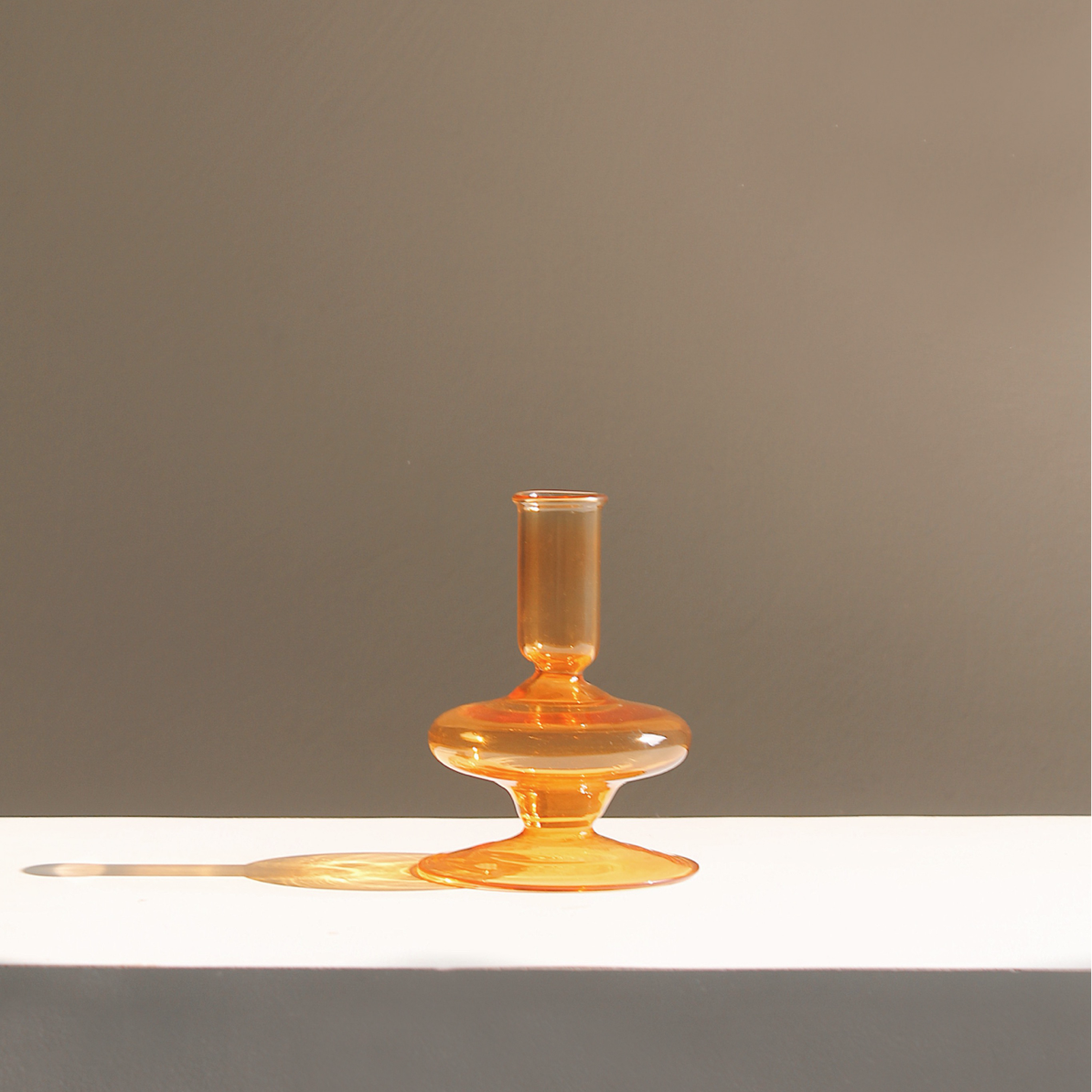 Amber Gigi glass candle holder casting a long shadow in daylight