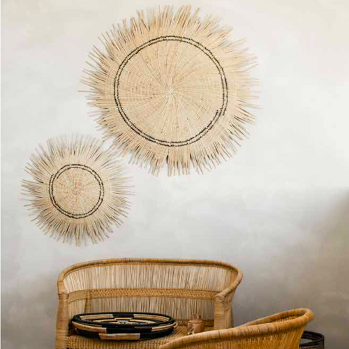 Two Sun Circle wall discs in different sizes above a woven bench