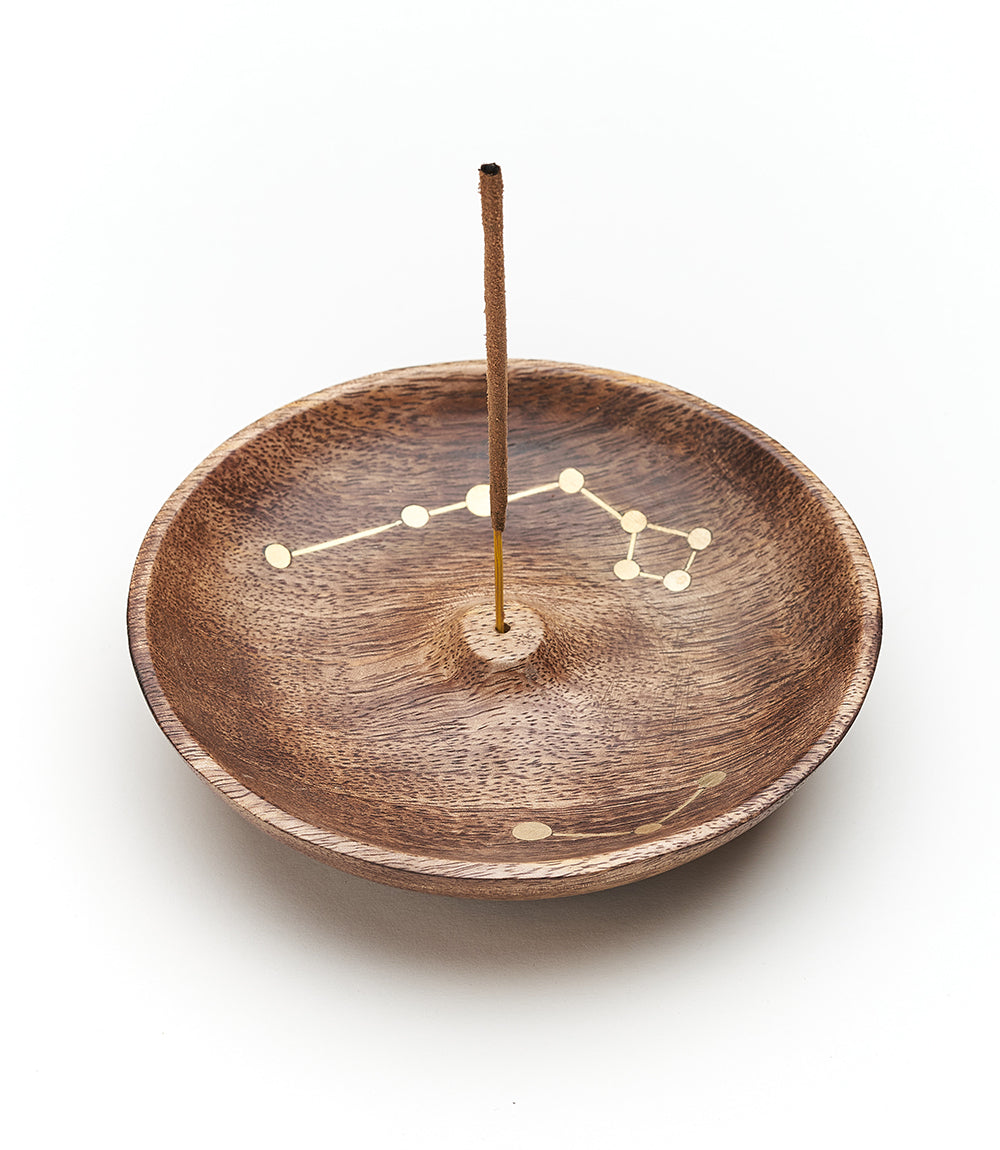 Jyotisha wood incense holder with an incense stick upright in the center hole