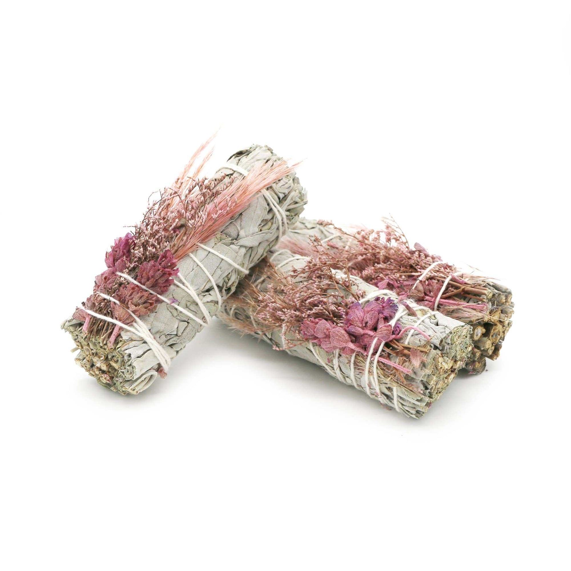 White sage smudge stick wrapped with a bouquet of pink dried flowers, shown from another angle