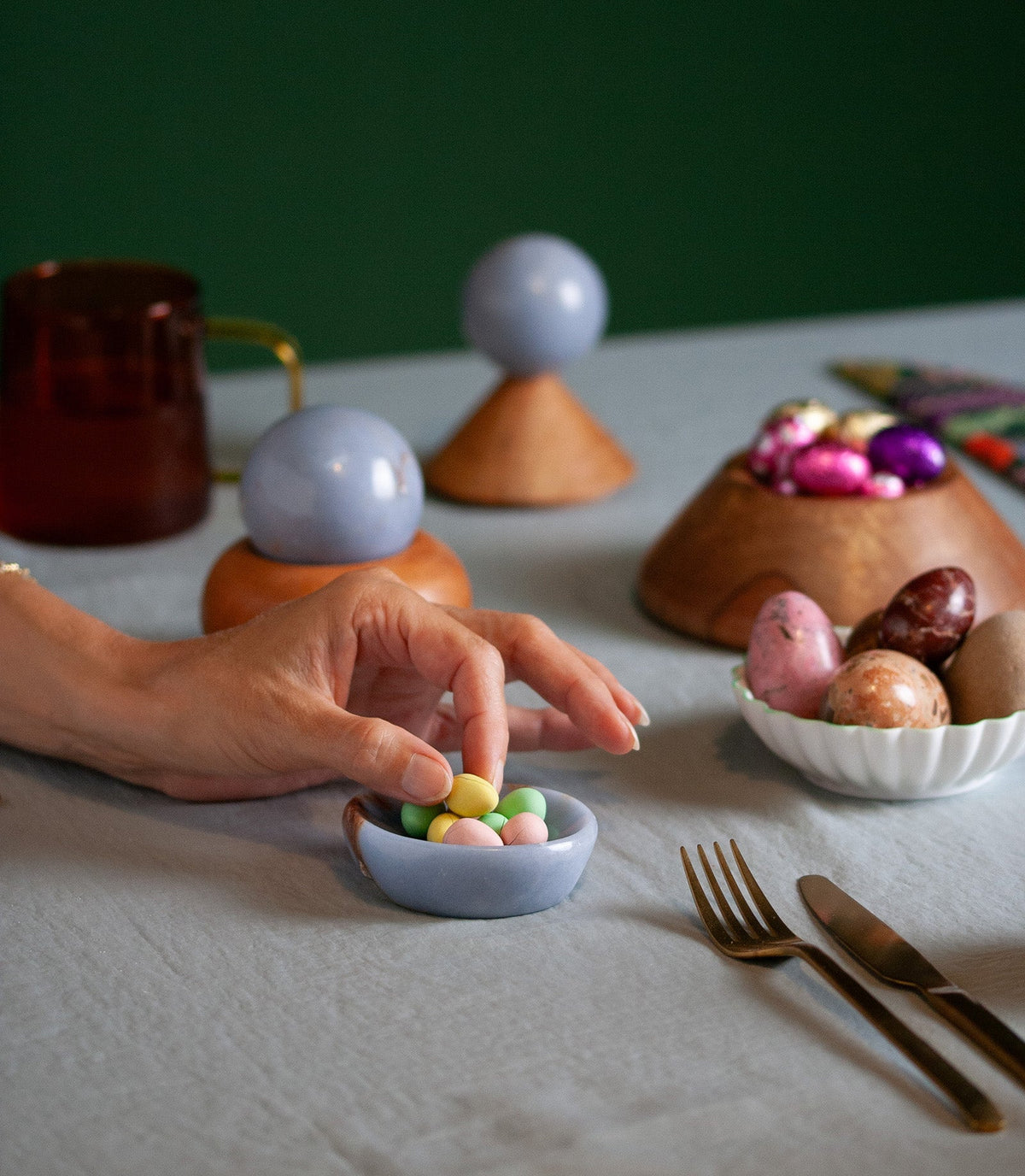 Angelite dish filled with sugared sweets on a laid table, hands reaching in