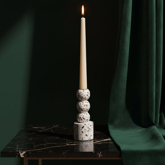 Centro terrazzo taper holder, stacked spheres on a cylinder base, with a lit ivory taper on dark marble