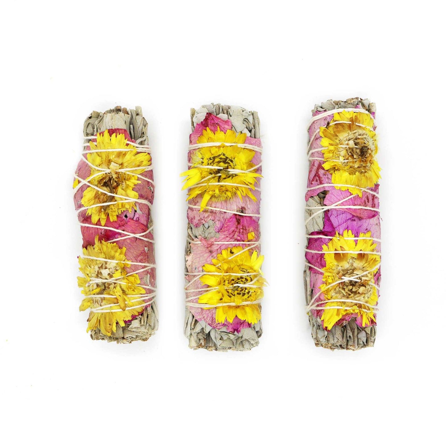Close view of the pink rose petals and sunflowers bound into a white sage bundle