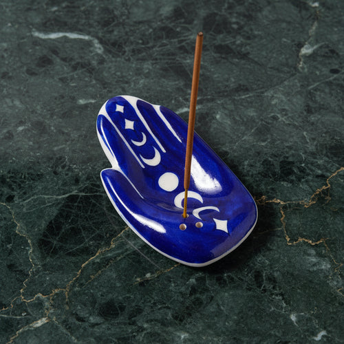 Cobalt blue hamsa hand incense holder painted with moon phases, on green marble